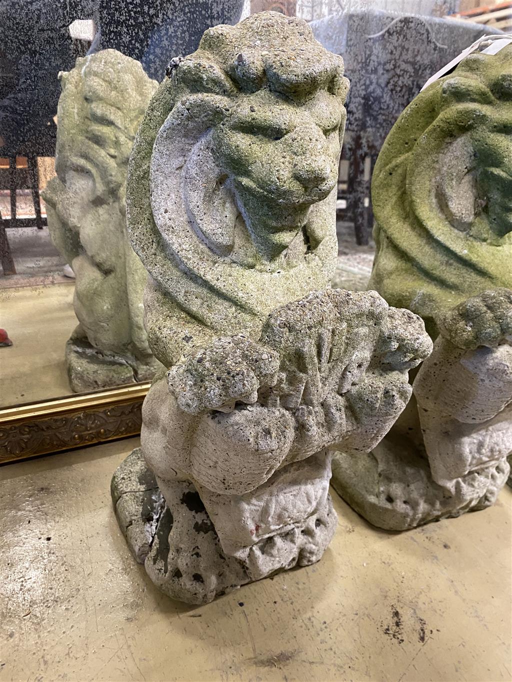 A pair of reconstituted stone lion and shield garden ornaments, height 56cm